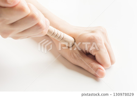 Pressing acupressure points on the hands with an acupressure stick - stock photo 130978029