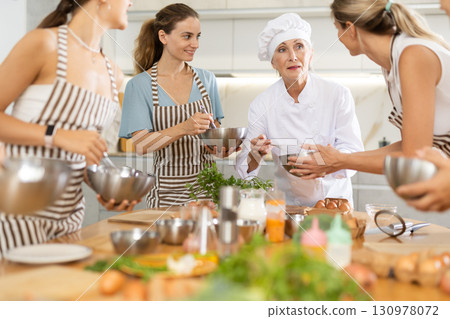 Mature female cook holding bowl and whisk 130978072