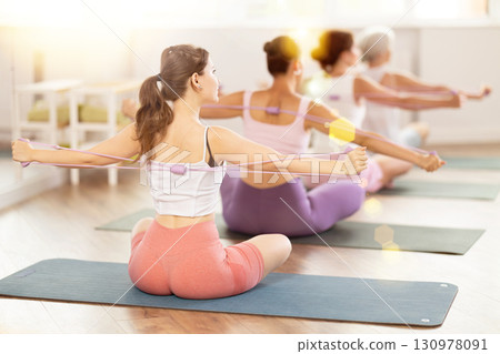 Group of women exercising with pilates loop back view 130978091
