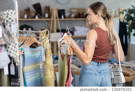 Adult woman choosing summer clothes in store Adult woman choosing summer clothes in store 130978101
