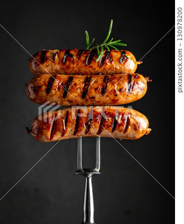 Cooking a delicious meal of roasted pork sausages on the grill for a hot barbecue 130978200