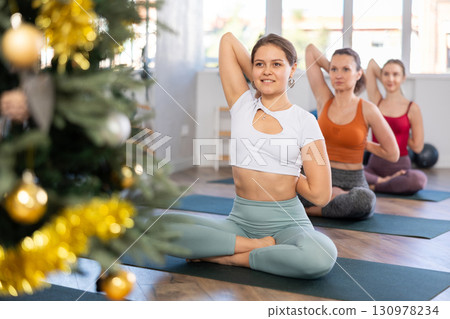 Girl teacher conduct yoga lesson for girls and performs lotus pose in New Year atmosphere. 130978234