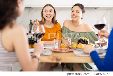 Girlfriends chatting and drinking wine in kitchen Girlfriends chatting and drinking wine in kitchen 130978238