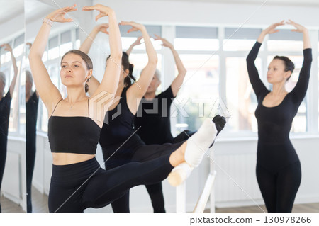 Young female ballet dancer performing developpe at barre in studio 130978266