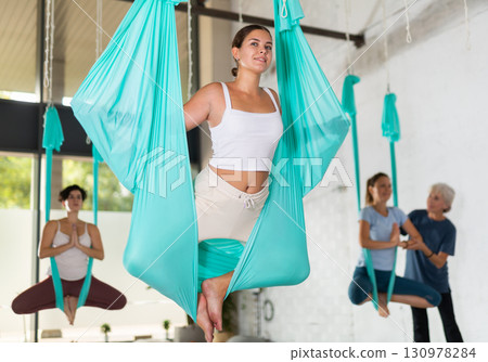 Fit young woman doing fly yoga stretching exercises in fitness training gym loft classroom. Sport healthy lifestyle concept 130978284