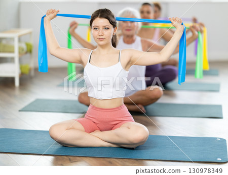 Young woman exercising with pilates band Young woman exercising with pilates band 130978349
