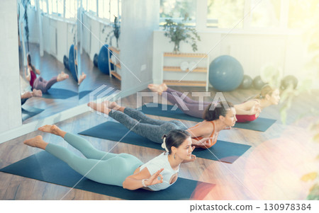 Girl teacher conducts lesson, training for girls in yoga studio and performs locust pose 130978384