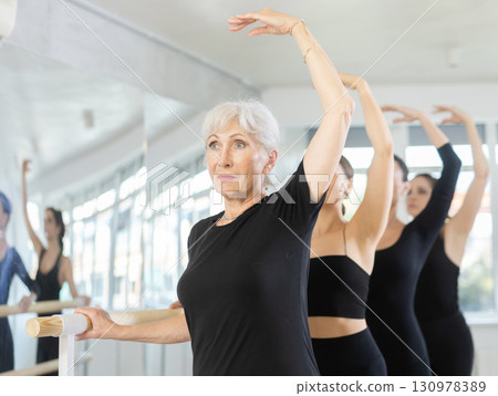 Senior lady mastering third position at ballet barre 130978389