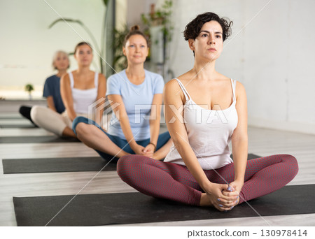 Latin female practicing Butterfly Pose during group yoga training 130978414