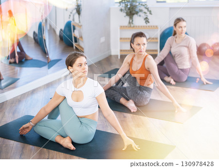 Girl teacher conducts lesson, training for girls in yoga studio and performs Lord of fishes pose. Girl teacher conducts lesson, training for girls in yoga studio and performs Lord of fishes pose. 130978428