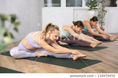 Active women perform a stretching exercise in a pose Janu Shirshasana Active women perform a stretching exercise in a pose Janu Shirshasana 130978450