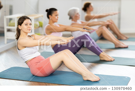 Young girl doing sit-ups at group pilates class 130978460