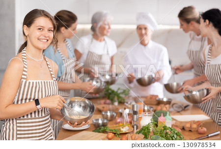Girl while studying at culinary workshop, cooks appetizing sauce, marinade, dough in bowl. Girl while studying at culinary workshop, cooks appetizing sauce, marinade, dough in bowl. 130978534