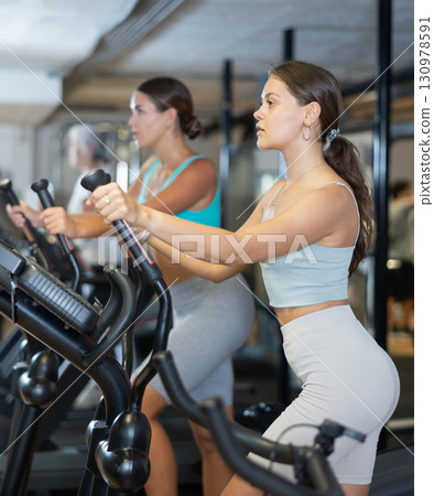 Sporty girl working out on elliptical machine in gym. Healthy active lifestyle concept Sporty girl working out on elliptical machine in gym. Healthy active lifestyle concept 130978591