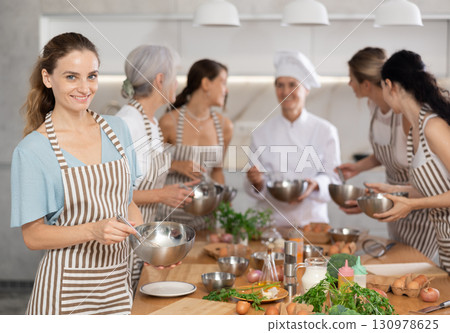Girl while studying at culinary workshop, cooks appetizing sauce, marinade, dough in bowl. Girl while studying at culinary workshop, cooks appetizing sauce, marinade, dough in bowl. 130978625