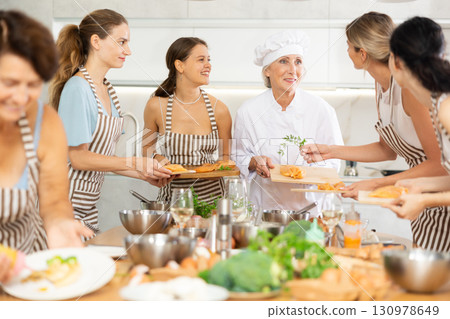 Elderly woman chef teaches group of people how to cook chicken Elderly woman chef teaches group of people how to cook chicken 130978649