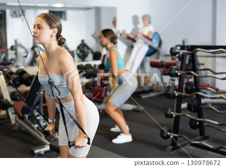 Active athlete young woman during exercises on crossover exercise machine with loops and weighting Active athlete young woman during exercises on crossover exercise machine with loops and weighting 130978672