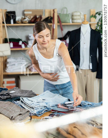 Adult woman choosing jeans in clothing store Adult woman choosing jeans in clothing store 130978757