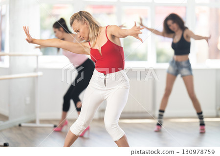 Female dancer performing sensual choreography in high heels at group rehearsal Female dancer performing sensual choreography in high heels at group rehearsal 130978759