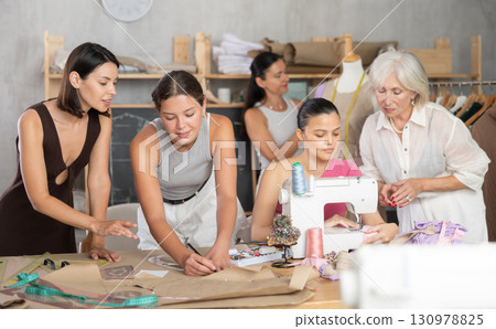 Group of women sew, draw pattern and work with mannequin 130978825