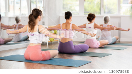 Group of women exercising with pilates loop back view 130978988