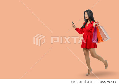 Young woman enjoys online shopping while carrying shopping bags 130979245