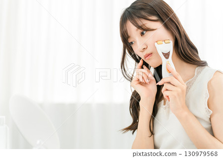 Young Asian woman having skin problems while massaging with a facial beauty device (skin care) 130979568