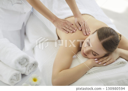 Relaxed woman lying down, massage in spa saloon, cosmetologist hands massaging, body relaxing 130980594