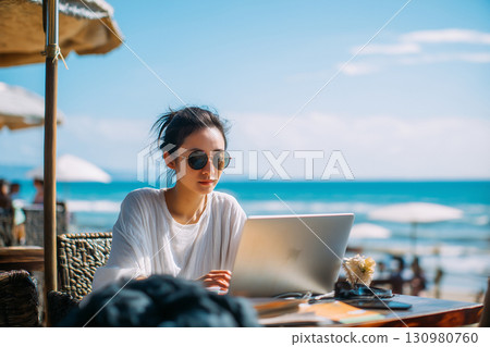 Woman using a computer at the beach Nomad worker 130980760