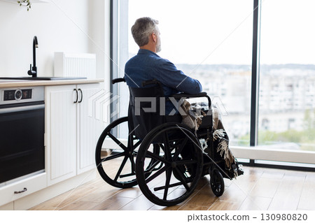 Senior man sitting in wheelchair gazing outside through window, embracing tranquility. Indoor setting with focus on accessibility, lifestyle, and reflective moment. Senior man sitting in wheelchair gazing outside through window, embracing tranquility. Indoor setting with focus on accessibility, lifestyle, and reflective moment. 130980820