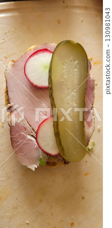 Savor the flavors of a Delicious OpenFaced Sandwich featuring Ham and crunchy Pickles 130981043