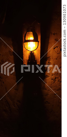 A Vintage Lantern Illuminates a Textured Wall, Creating a Cozy Nostalgic Atmosphere A Vintage Lantern Illuminates a Textured Wall, Creating a Cozy Nostalgic Atmosphere 130981073