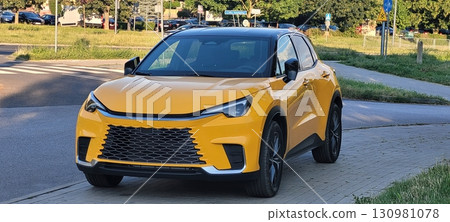 A stunning and vibrant yellow crossover SUV cruising on a scenic picturesque road A stunning and vibrant yellow crossover SUV cruising on a scenic picturesque road 130981078