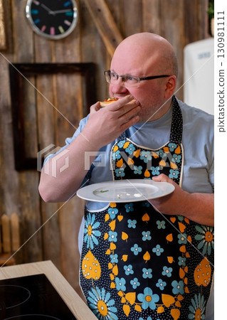 The Cheerful Chef is Tasting a Delicious Dish While Wearing a Colorful and Fun Apron The Cheerful Chef is Tasting a Delicious Dish While Wearing a Colorful and Fun Apron 130981111