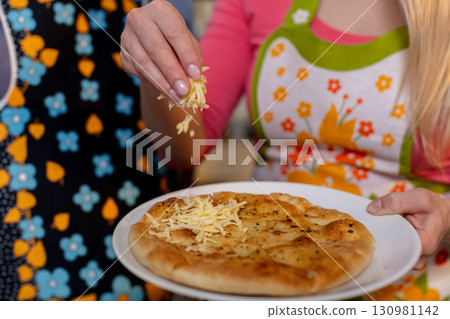 Indulge in the incredibly delicious preparation of homemade pizza with a cheesy topping Indulge in the incredibly delicious preparation of homemade pizza with a cheesy topping 130981142