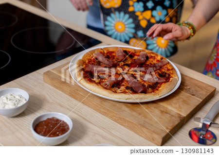 Indulge in a Delicious Homemade Pizza with a Variety of Toppings Arranged on a Wooden Board Indulge in a Delicious Homemade Pizza with a Variety of Toppings Arranged on a Wooden Board 130981143