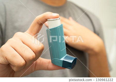 Asthma and chronic obstructive pulmonary disease COPD, Asian young man using metered dose inhaler MDI. 130981222