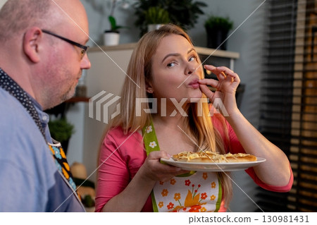 Enjoying a Delightful Cooking Moment Together with Friends in a Cozy and Welcoming Kitchen 130981431