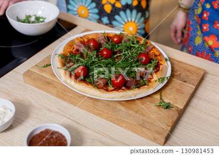 Delicious Freshly Made Pizza topped with Cherry Tomatoes and Arugula for everyone to enjoy 130981453