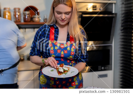 Culinary Creativity A Woman Delightfully Serving a Delicious Dish in the Comfort of Her Home Culinary Creativity A Woman Delightfully Serving a Delicious Dish in the Comfort of Her Home 130981501