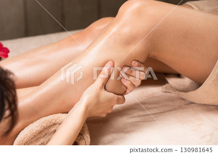 A young Asian woman is getting a leg oil massage. A young Asian woman is getting a leg oil massage. 130981645