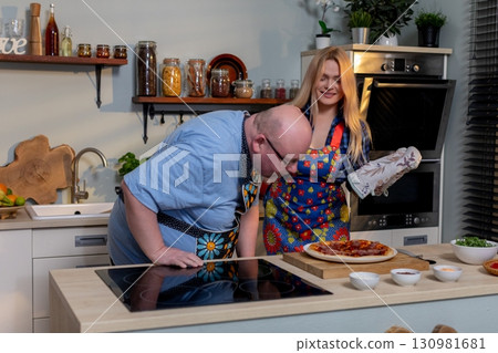 Chefs donning vibrant and colorful aprons are joyfully cooking together in a modern kitchen setting 130981681