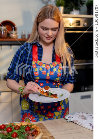 A Woman in a Colorful Apron Skillfully Cooking in a Modern, WellEquipped Kitchen A Woman in a Colorful Apron Skillfully Cooking in a Modern, WellEquipped Kitchen 130981707