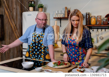 A talented culinary duo is busy in a cozy kitchen, skillfully preparing a vibrant and colorful dish 130981713