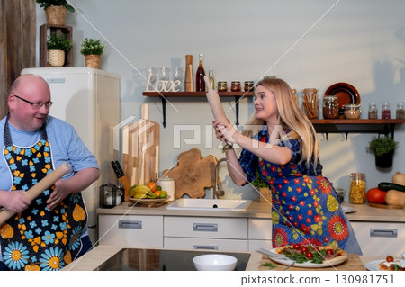 A Joyful and Fun Cooking Scene Featuring Playful Chefs Dressed in Colorful Aprons 130981751