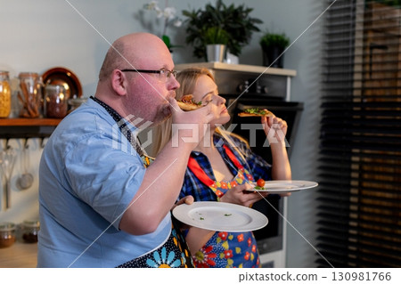 A Happy Couple Enjoying a Delicious Homemade Meal Together in Their Modern, Stylish Kitchen 130981766