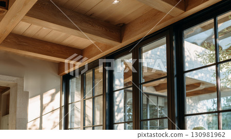 Modern window with black frame and wooden ceiling beams in bright room with natural light and outdoor view 130981962