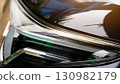 Abstract luxury of modern car headlights close up. Sparkling light of the lamp and the dark color of the car body reflect the orange light. 130982179