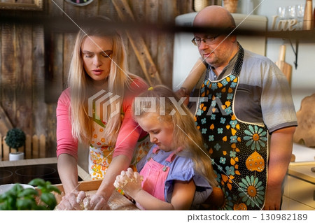 A Family Cooking Together while Creating Cherished Memories in a Cozy Kitchen Setting A Family Cooking Together while Creating Cherished Memories in a Cozy Kitchen Setting 130982189