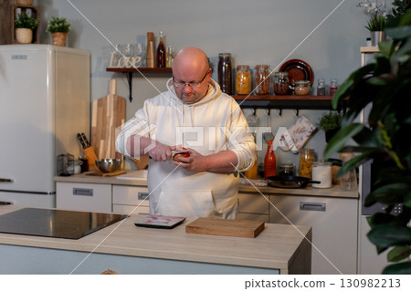 A chef is skillfully preparing fresh ingredients in a beautifully designed modern kitchen 130982213